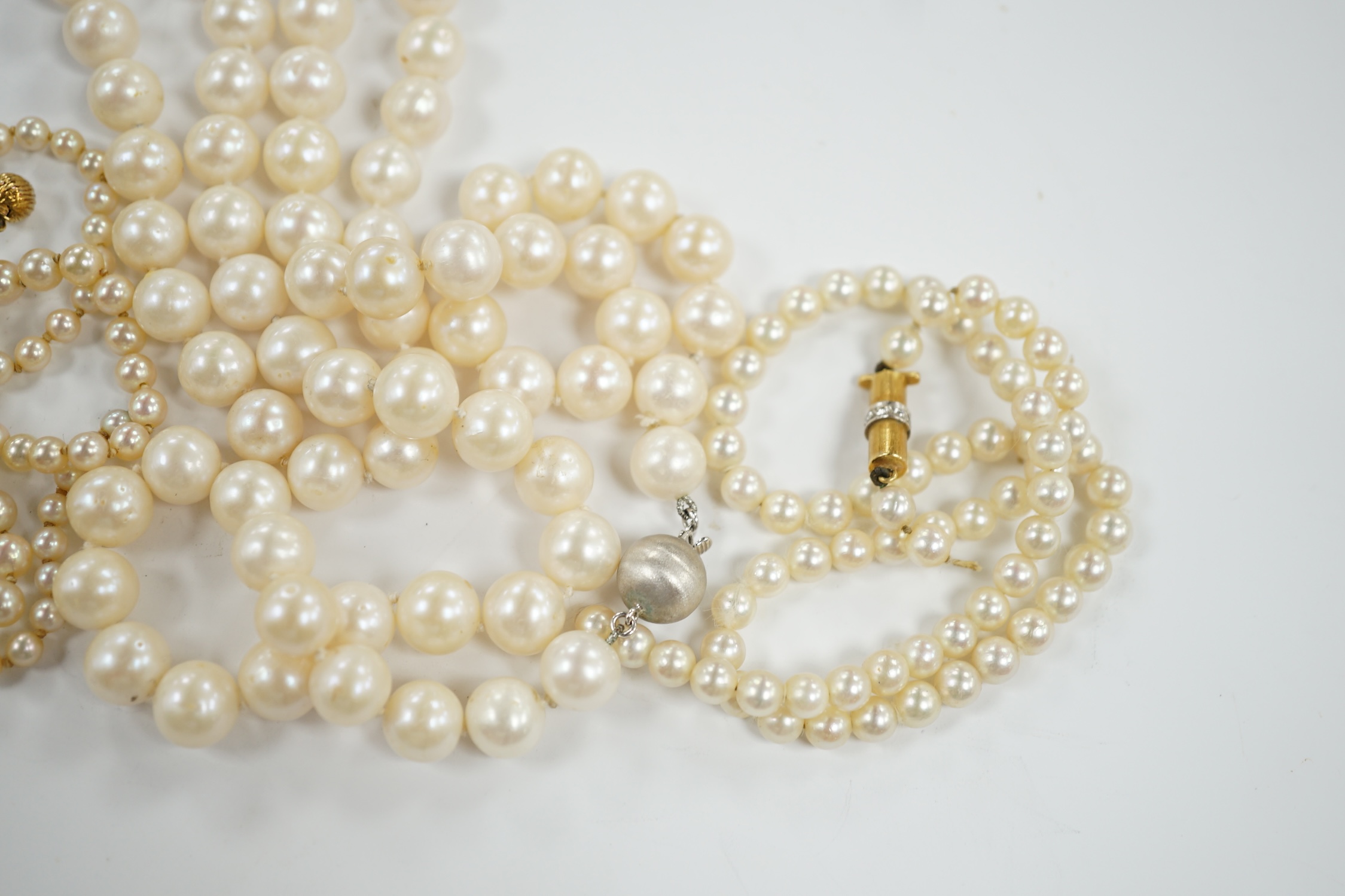A single strand cultured pearl necklace with 18k white metal clasp, 88cm and two other similar smaller necklaces, with yellow metal clasps(both need re-stringing).
